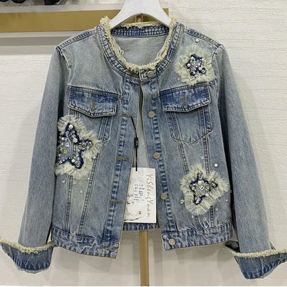 cette veste en jean pour femme présente de lourdes perles inspirées de l'industrie et un design à col rond. C'est une option de vêtement d'extérieur à la mode et courte.