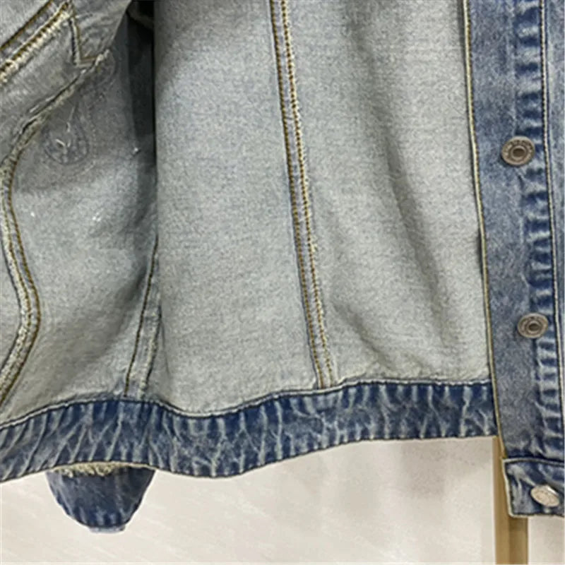 cette veste en jean pour femme présente de lourdes perles inspirées de l'industrie et un design à col rond. C'est une option de vêtement d'extérieur à la mode et courte.