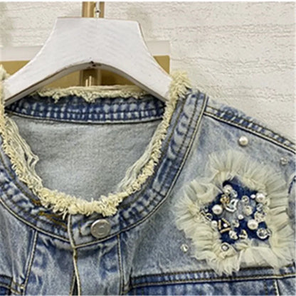 cette veste en jean pour femme présente de lourdes perles inspirées de l'industrie et un design à col rond. C'est une option de vêtement d'extérieur à la mode et courte.